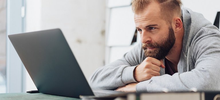 junger Mann lernt mit Laptop und schriftlichen Unterlagen