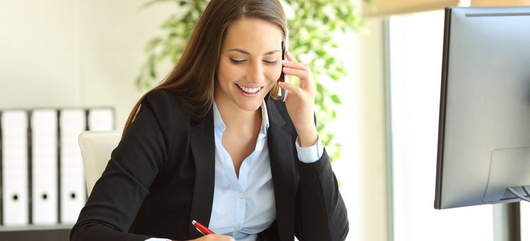 Beraterin telefoniert am Schreibtisch und macht Notizen