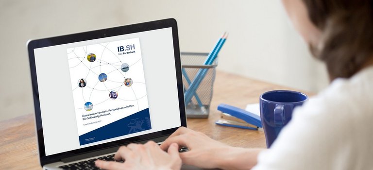 Frau liest am Laptop den IB.SH-Geschäftsbericht 2019
