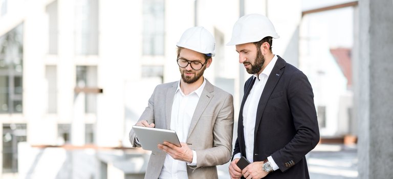 Zwei Bauherren planen mithilfe eines Tablets auf einer Baustelle