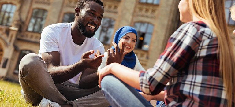 Drei lachende junge Menschen aus unterschiedlichen Kulturkreisen im Gespräch