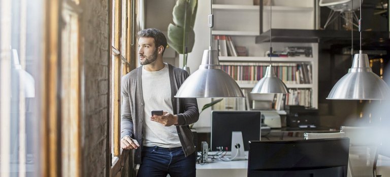 Junger Unternehmer steht in Start-up-Büro am Fenster