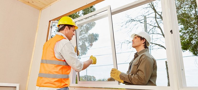 Zwei Bauarbeiter setzen Fenster in Wohnhaus ein