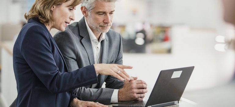 Businessfrau und Businessmann schauen gemeinsam auf Laptop-Bildschirm